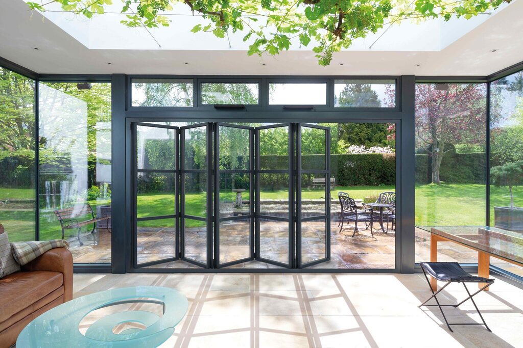 GFD Homes Front doors UK: 5 Panel Smart Heritage Industrial Style Bifold Door installed in living room with garden views. 