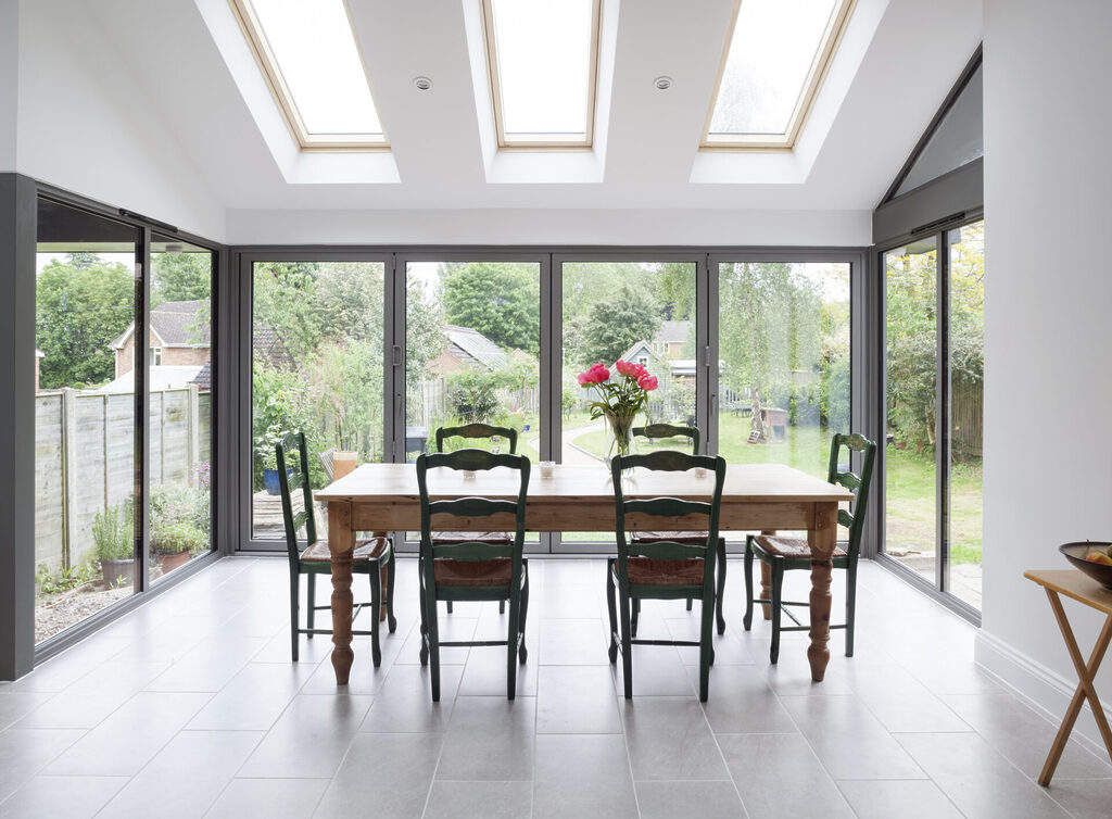 GFD Homes How much are bifold doors: 3 Panel Smart Bifold in White, installed in living room with dining table. 