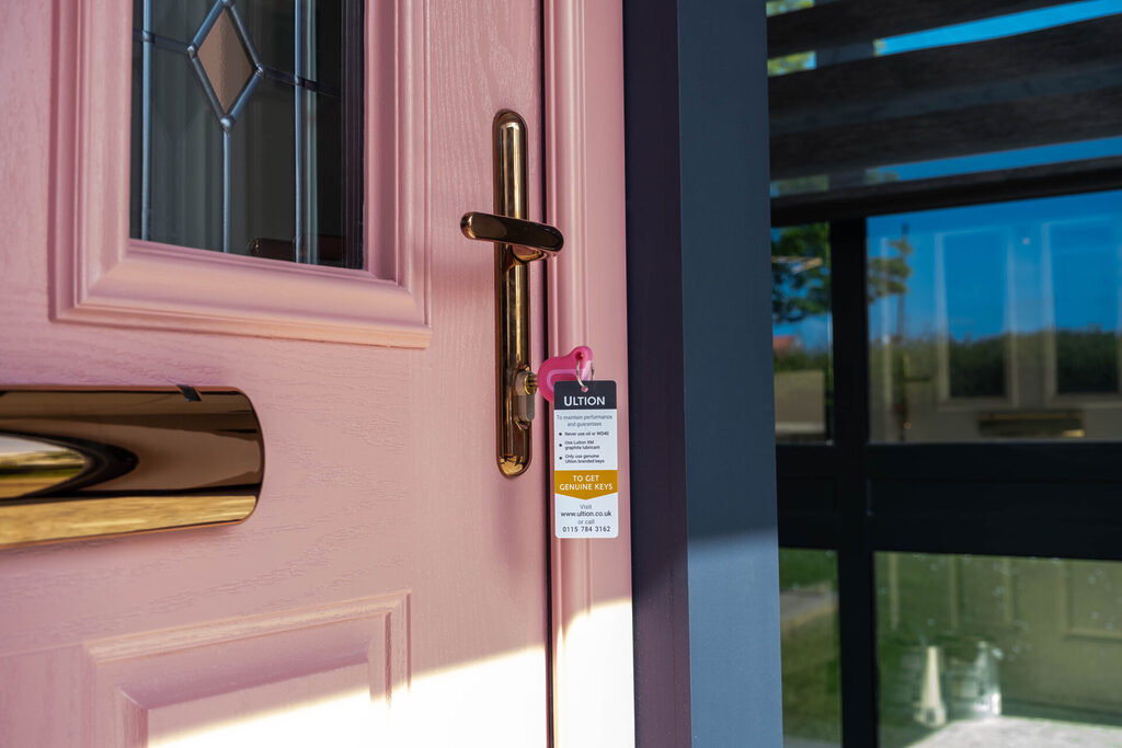GFD Homes External door frame: Pink coloured composite door in our GFD Homes showroom with a sculptured edge.
