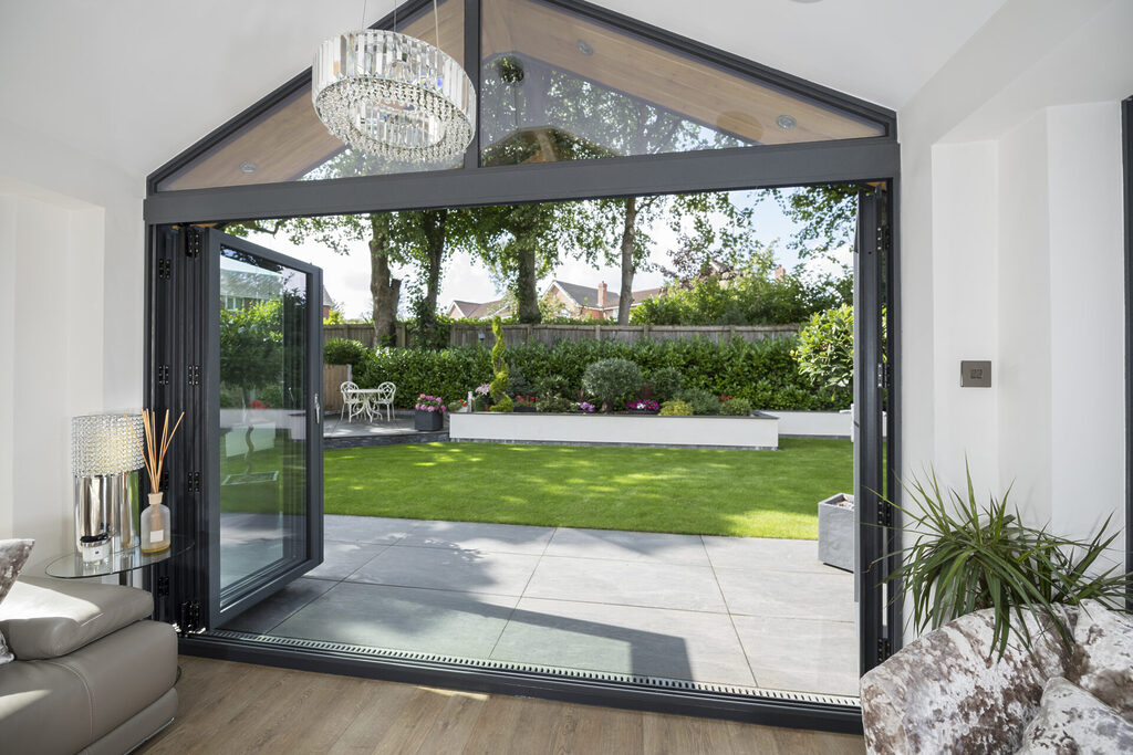 GFD Homes how to open bifold doors : Interior shot looking out into a well kept garden of an open bifold door