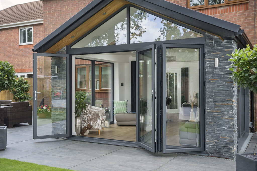 do you need planning permission for bifold doors: exterior shot of bifold doors open and slid to the side looking into an orangery
