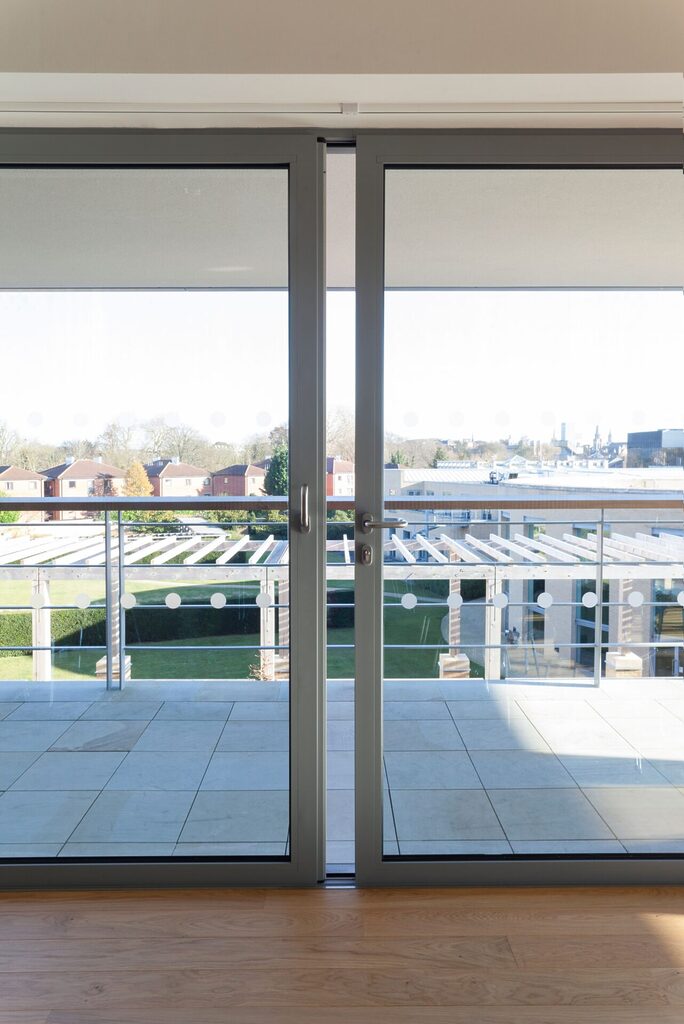 GFD Homes aluminium sliding patio doors slightly ajar looking out onto a tiled patio area 