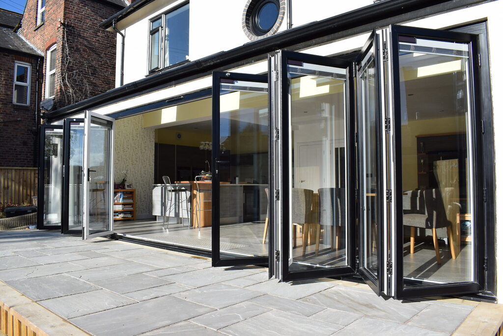 GFD Homes do bifold doors add value : Large bifold door with a white traffic door and the rest coloured black. 