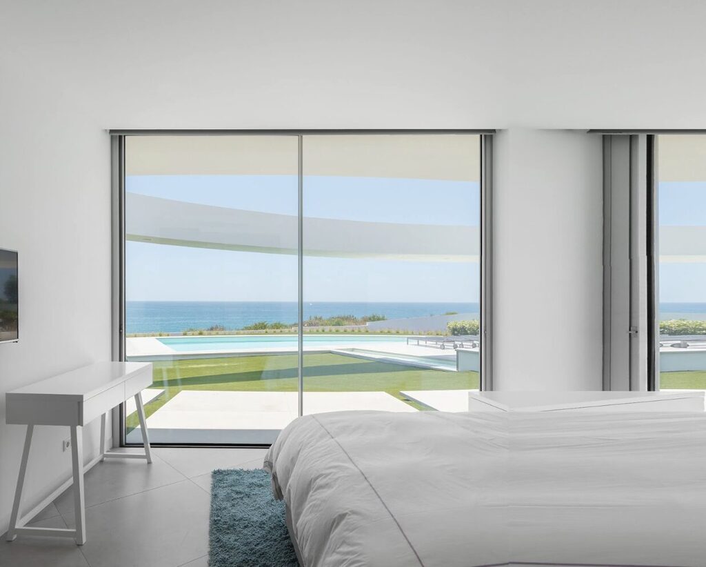 GFD Homes how do you adjust a sliding glass door: Cortizo sliding doors installed in bedroom with swimming pool and sea in view. 