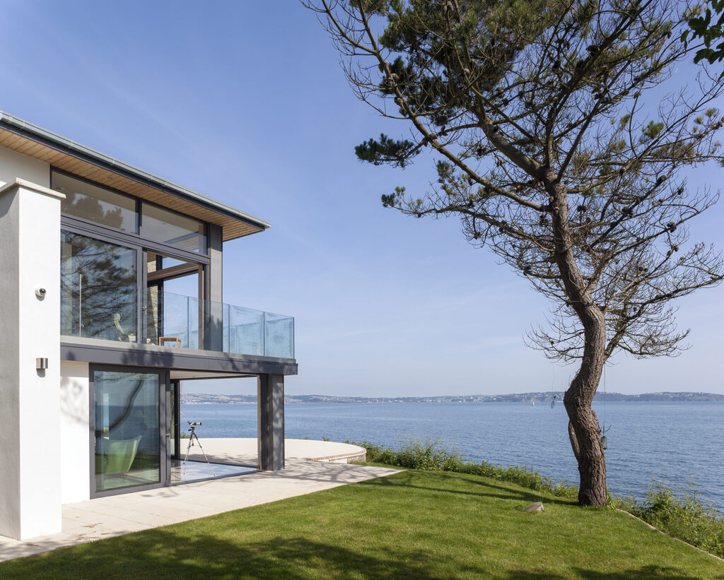 GFD Homes sliding aluminium doors : exterior shot of a water front property with it's sliding aluminium doors slid open 