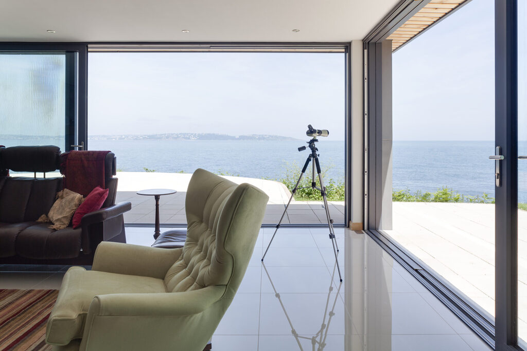 GFD Homes sliding aluminium doors: sliding patio door open with sea view in sight.