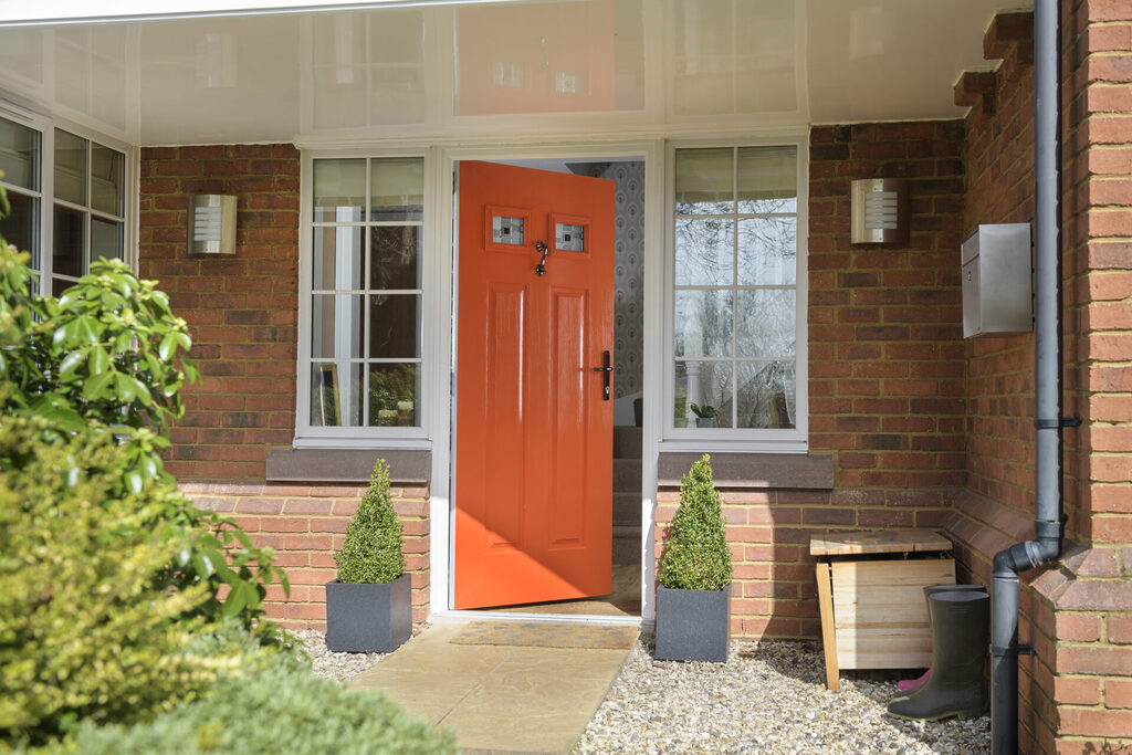 GFD Homes how to make your home more energy efficient: exterior shot of a bright orange door that has ajar 