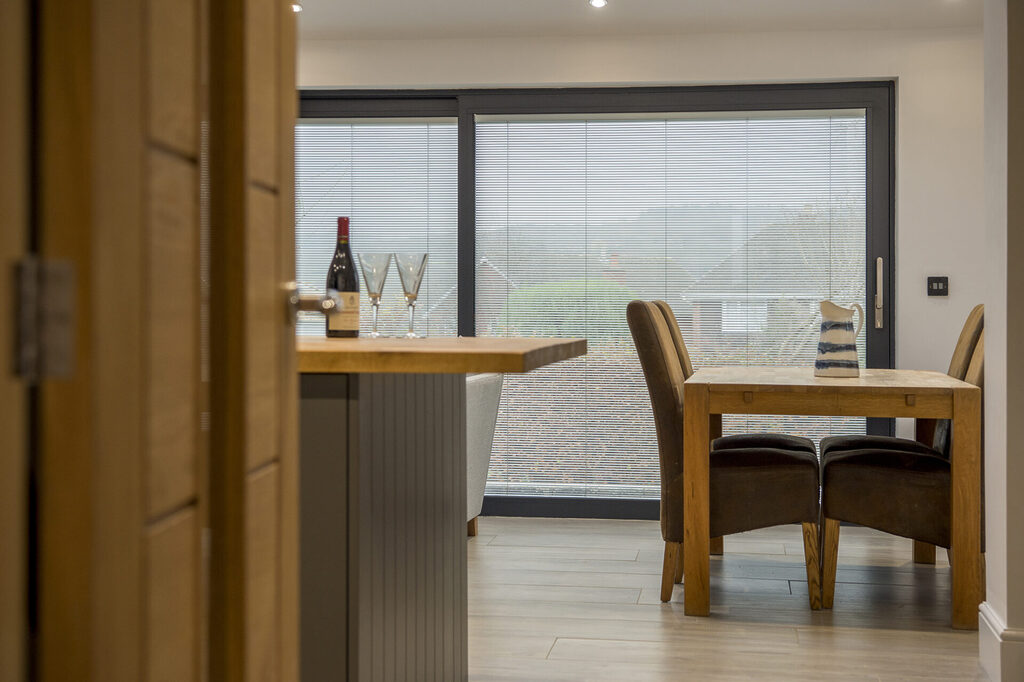 GFD Homes benefits of sliding doors : looking through a well kept kitchen to their sliding door with integral blinds