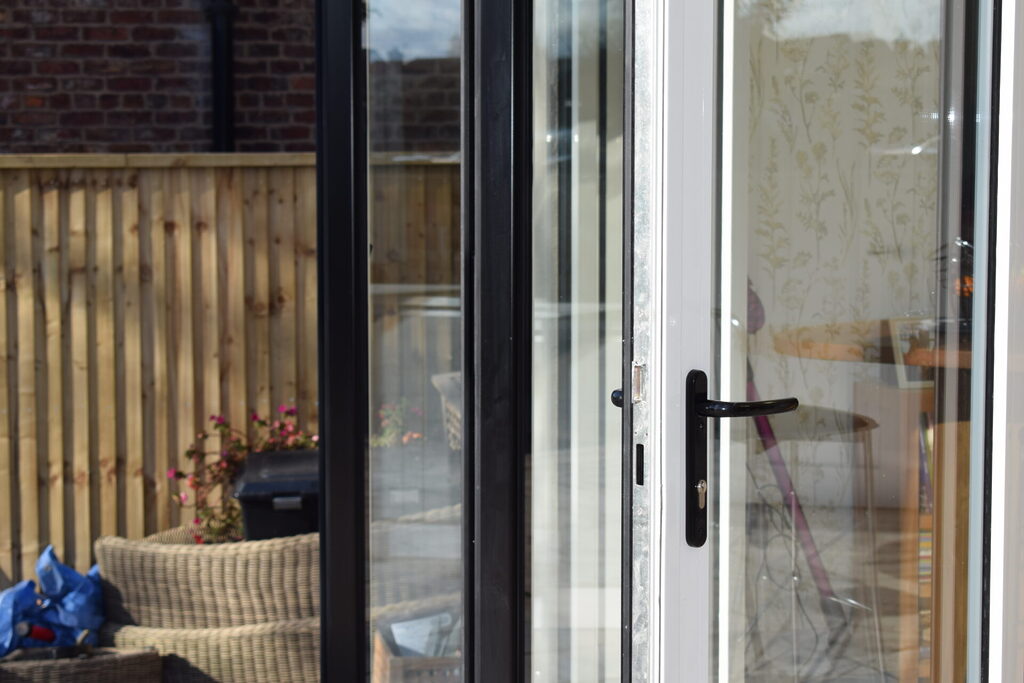 GFD Homes ce meaning : French doors opening onto the patio with one side black and the other, white. 