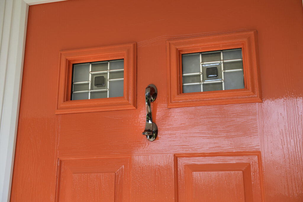 GFD Homes Solidor : Tangerine solidor composite door close up with 2 small windows and a knocker