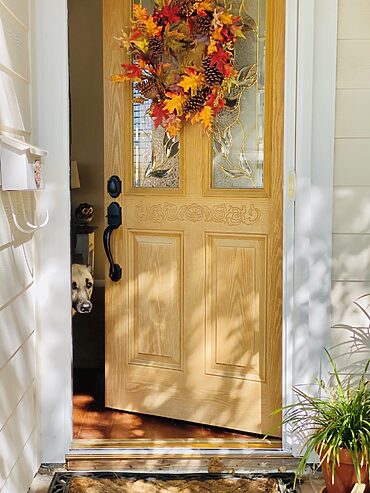 changing a door: door half open with autumn wreath on front door.