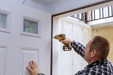 how to fit a door frame: fitter screwing door hinges in place.