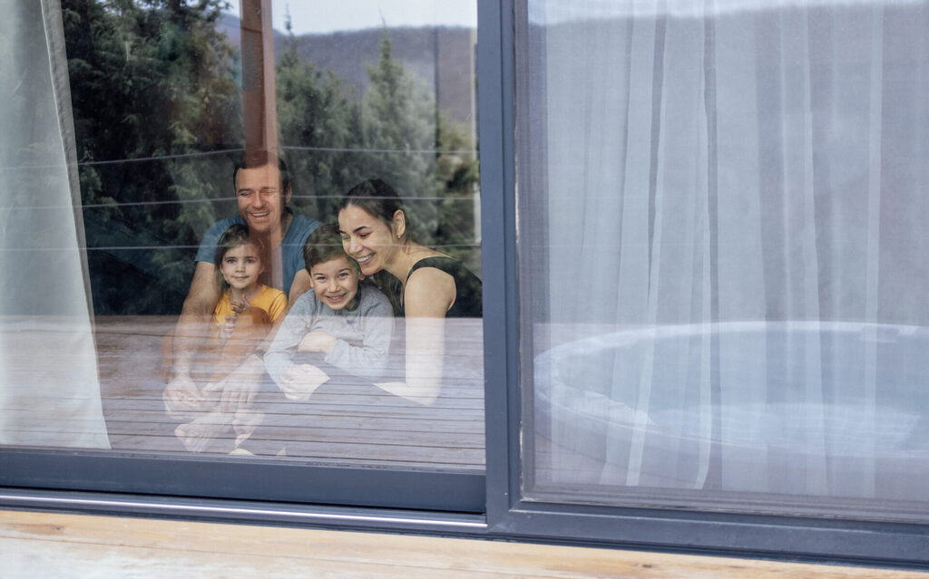 GFD Homes benefits of triple glazing: sliding door with family sat down smiling in view. 