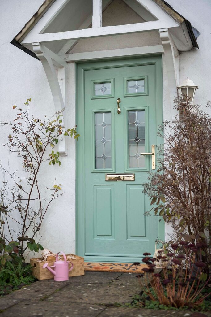 Fitted Composite Doors: Comp Door in chartwell green with watering pot next to door. 