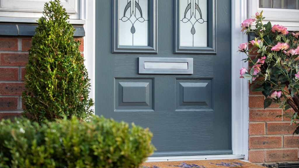 door colours: Bottom half of door zoomed in with greenery around the door. 