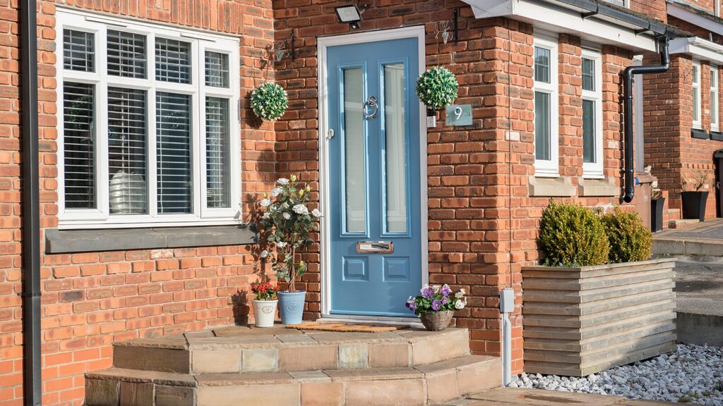 composite front doors: new blue door with flower pots around entrance